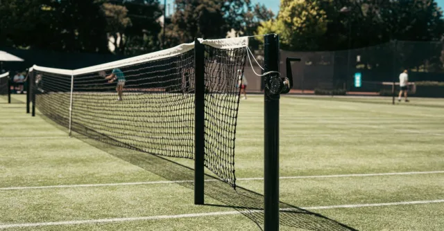 Grass tennis court with net at park in Melbourne, Australia. Perfect for leisure and sports enthusiasts.