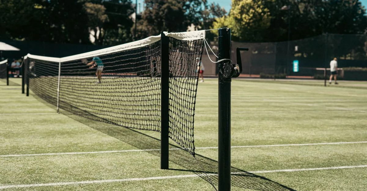 Grass tennis court with net at park in Melbourne, Australia. Perfect for leisure and sports enthusiasts.
