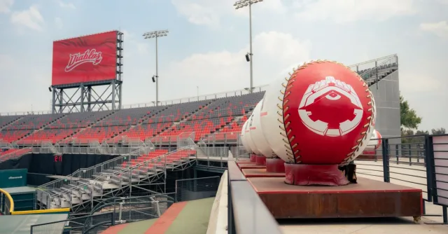 A view of an empty stadium with oversized baseball decorations under a clear sky.