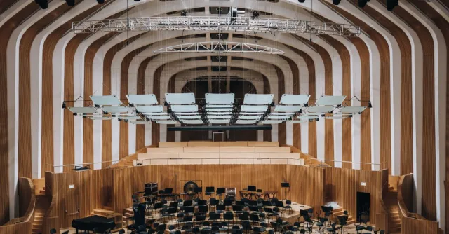 Spacious modern auditorium featuring wooden interior architecture and empty seating.