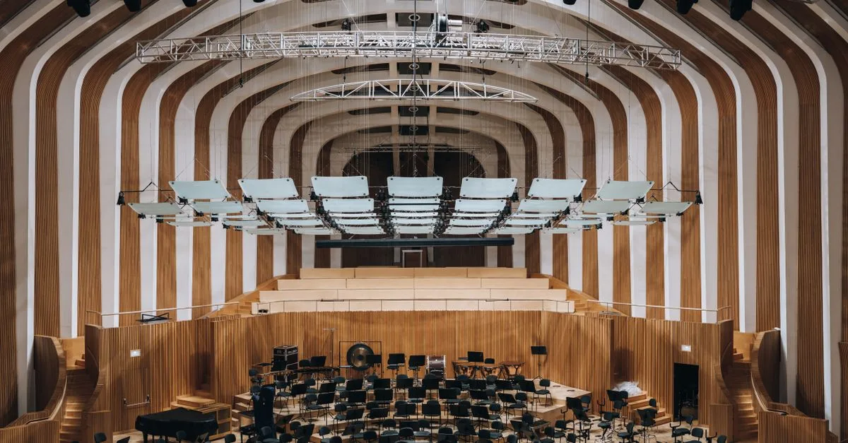 Spacious modern auditorium featuring wooden interior architecture and empty seating.
