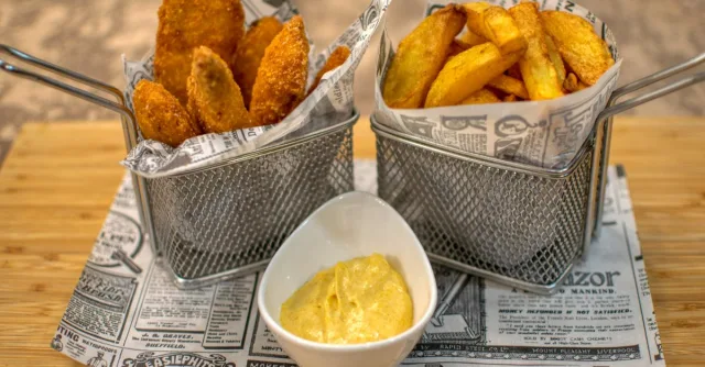 Delicious crispy chicken tenders served with fries and dipping sauce in a restaurant setting.