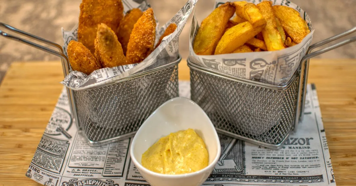 Delicious crispy chicken tenders served with fries and dipping sauce in a restaurant setting.