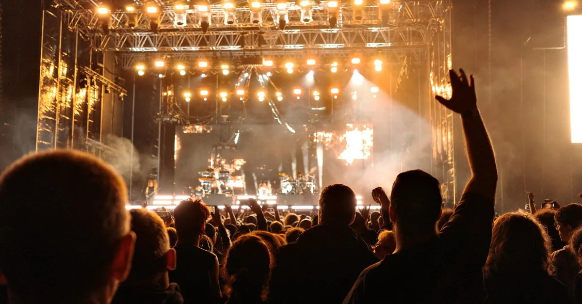 Energetic night concert with a cheering crowd and bright stage lights creating an electrifying atmosphere.