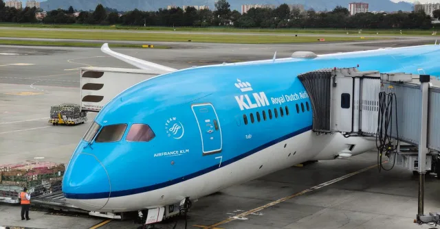 KLM airplane at boarding gate in Bogotá airport with mountain backdrop, ready for departure.