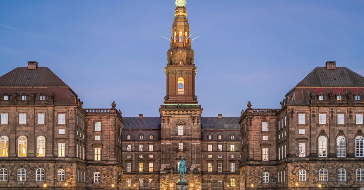 Stunning evening view of Christiansborg Palace with its illuminated spire in Copenhagen, Denmark.