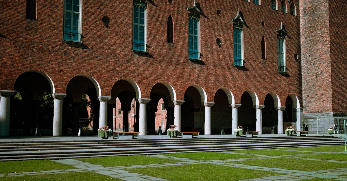 A view of the iconic Stockholm City Hall featuring a brick facade with arches and columns.
