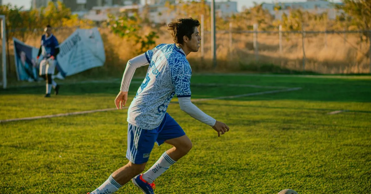 Teen soccer player dribbles the ball on a sunny day outdoor field.