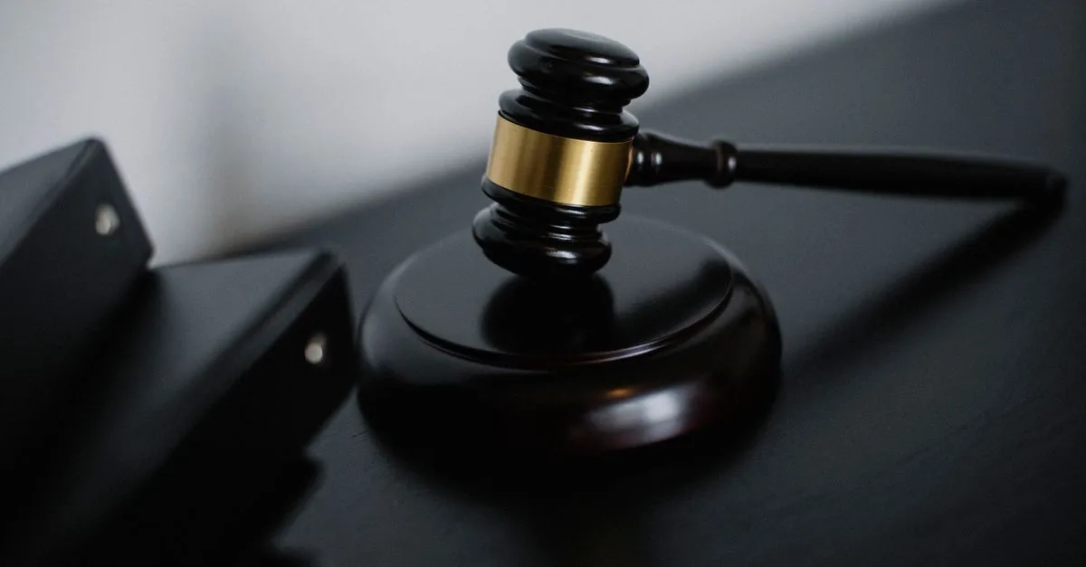 High angle of shiny wooden ceremonial mallet with golden detail placed on judge tale near documents folders