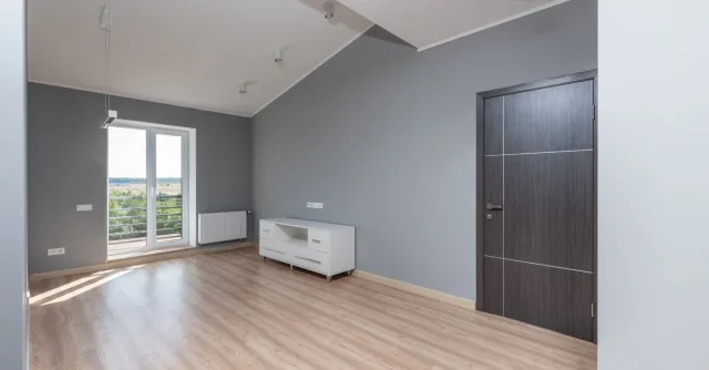 Bright and empty modern room with hardwood floors and large window view.