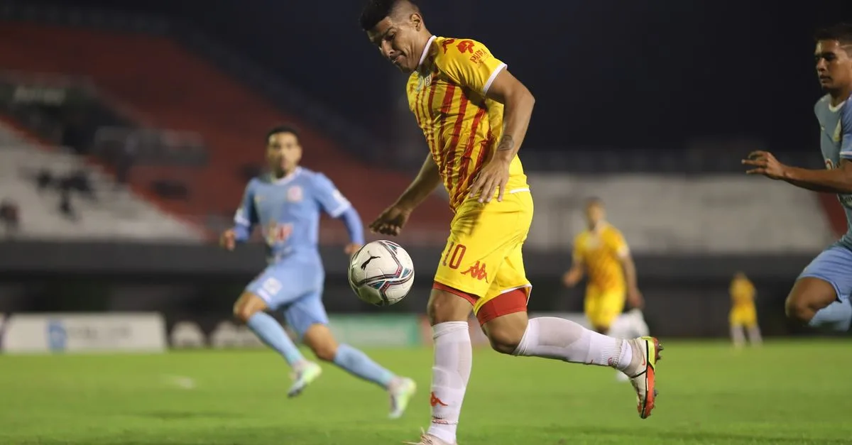 Soccer players in action during a competitive night match on a well-lit football field.