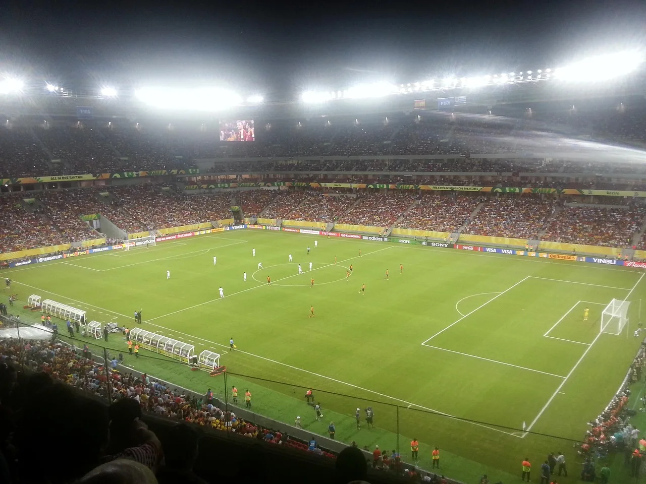 A professional football stadium illuminated by bright floodlights at night.