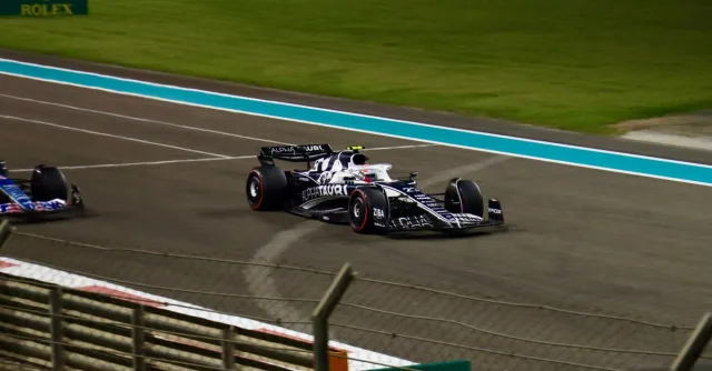 Formula 1 cars racing at night on the Yas Marina Circuit in Abu Dhabi.