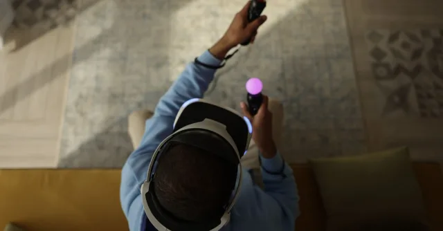 Top view of an adult playing with a VR headset and controllers indoors, emphasizing immersive gaming.