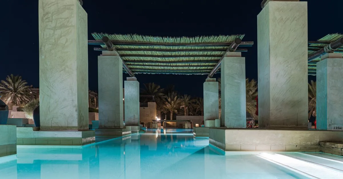 Stunning poolside view of a luxury hotel in Dubai by night, perfect for relaxation.