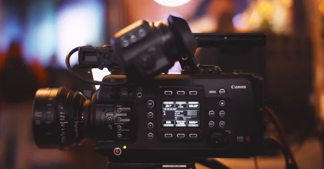 Close-up of a professional video camera in a studio environment, showcasing lens and controls.