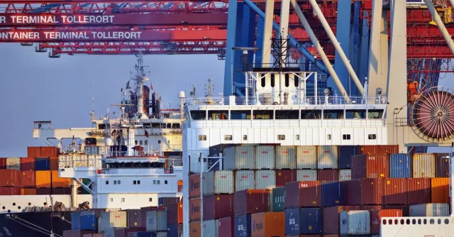 Container ships docked at Tollerort Terminal, Hamburg during sunset.