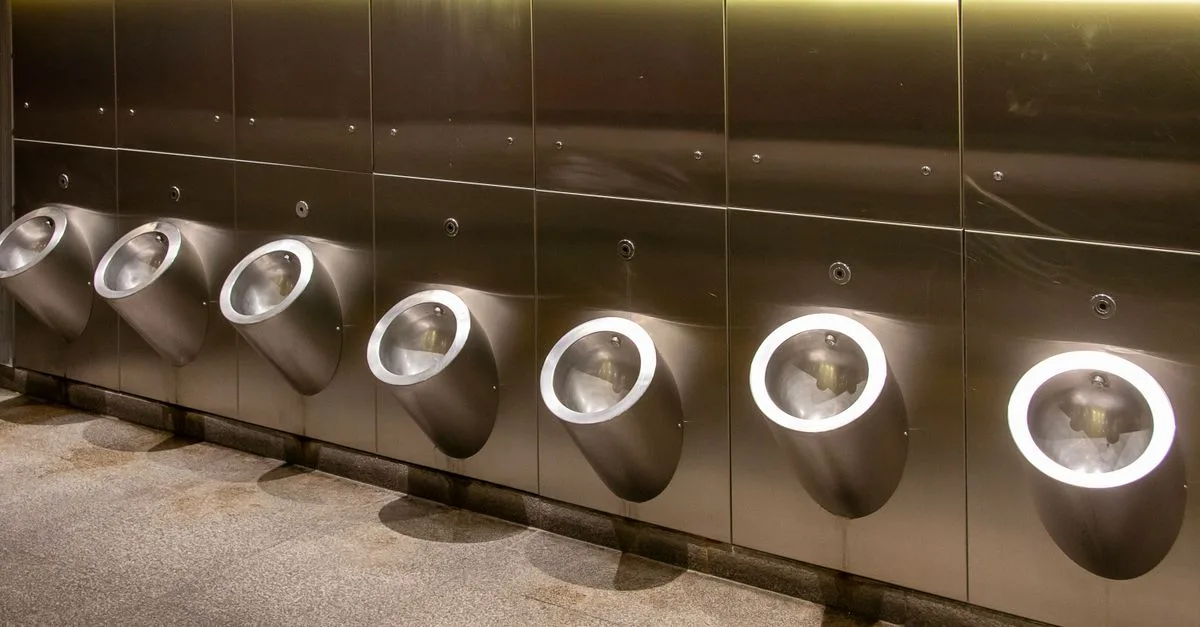 Row of modern stainless steel urinals in a public bathroom, clean and minimalistic design.