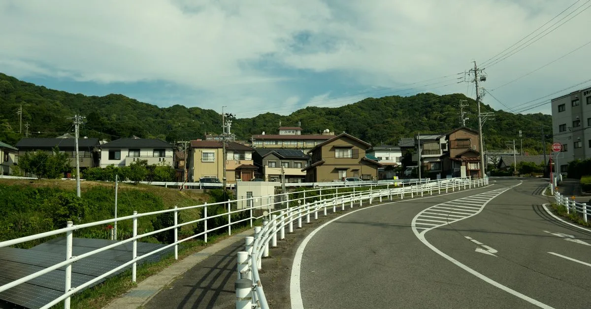Curved road through suburban Gamagōri, Japan, with traditional houses and lush hills.