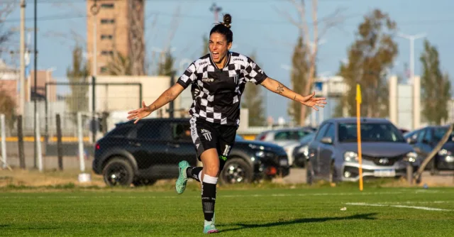 A female footballer celebrates a goal during a match, showcasing her passion and excitement.