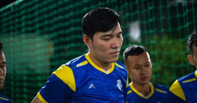 Asian football team gathers in vibrant uniforms during a night game. Focus on teamwork and sportsmanship.