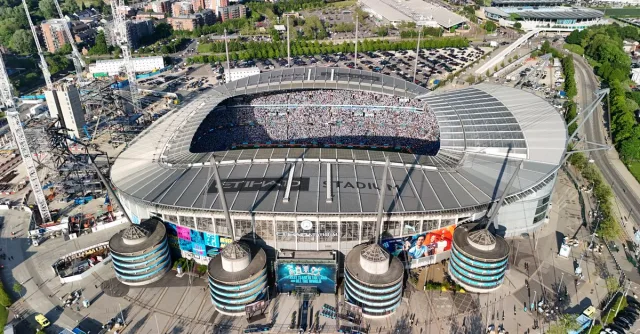 Drone shot of a packed Etihad Stadium in Manchester, England, showcasing a vibrant cityscape.