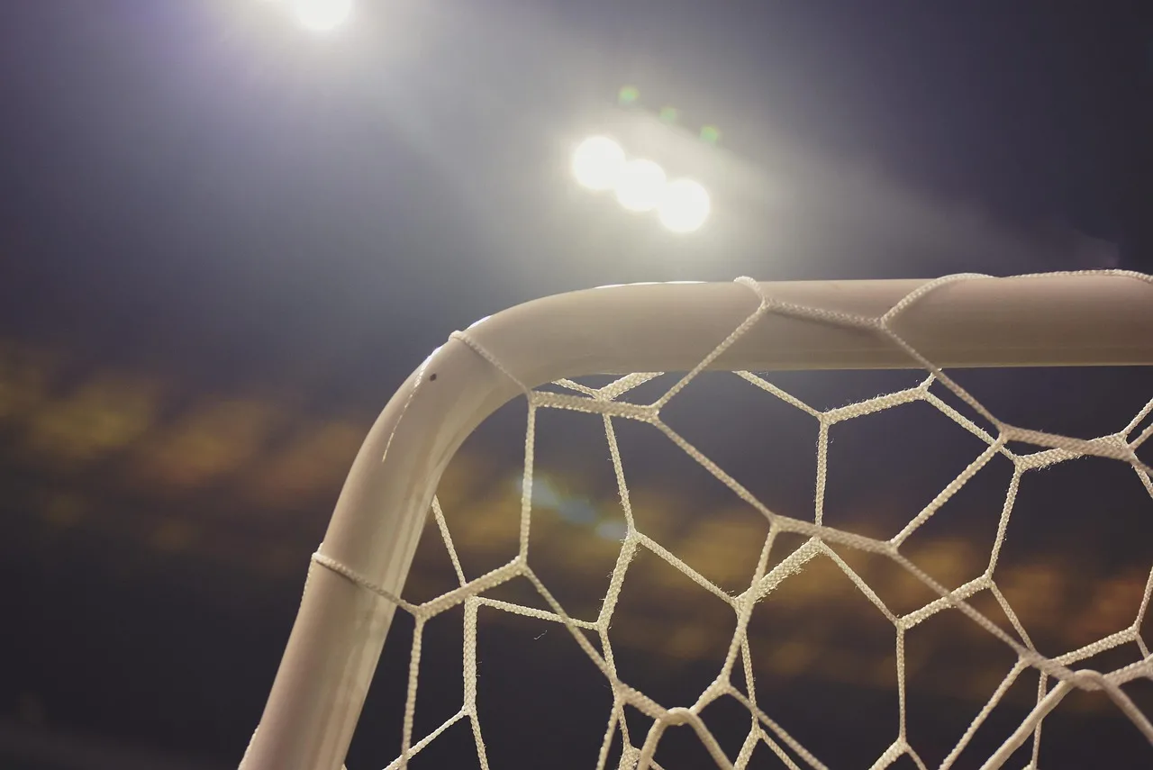 A professional football stadium illuminated by bright floodlights during a night match.