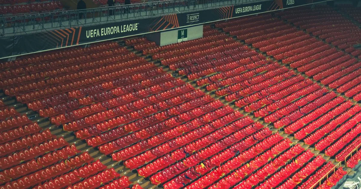 Empty red stadium seats at UEFA Europa League venue, providing spacious copyspace.