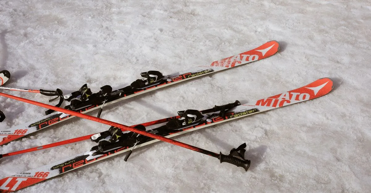 Red and black skis and poles resting on snow, suggesting a winter sports scene.