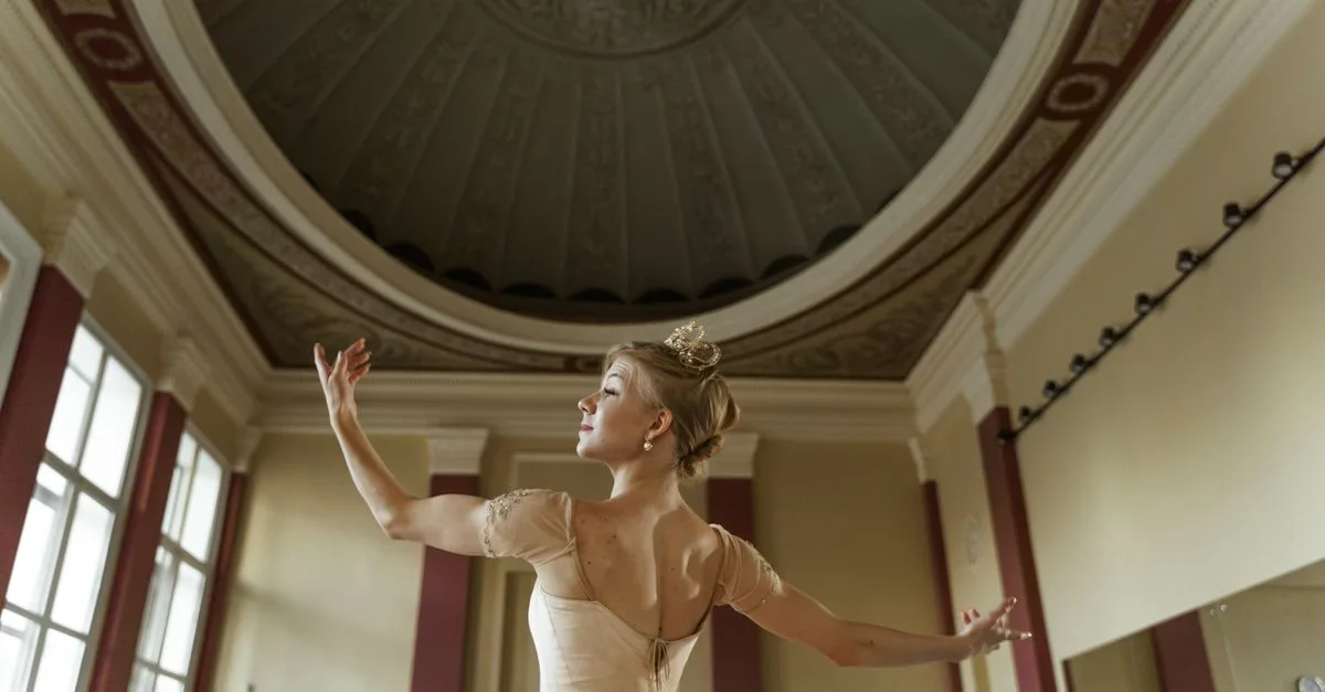 A ballerina elegantly poses in a grand hall, showcasing poise and grace.