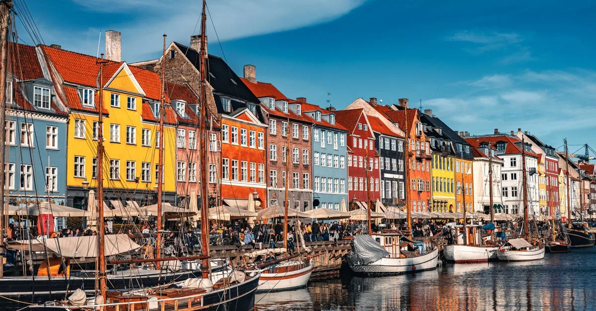 Vibrant view of Nyhavn with boats and colorful buildings in Copenhagen, Denmark.