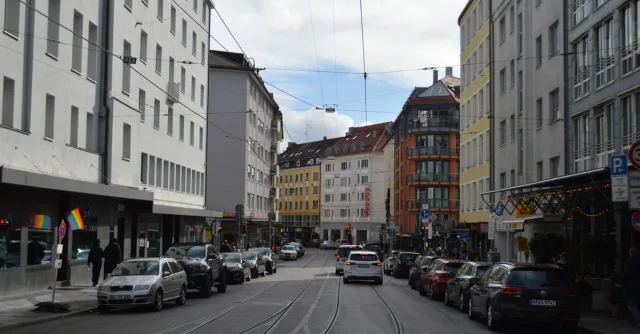Urban street view with buildings, cars, and tramlines during the day.