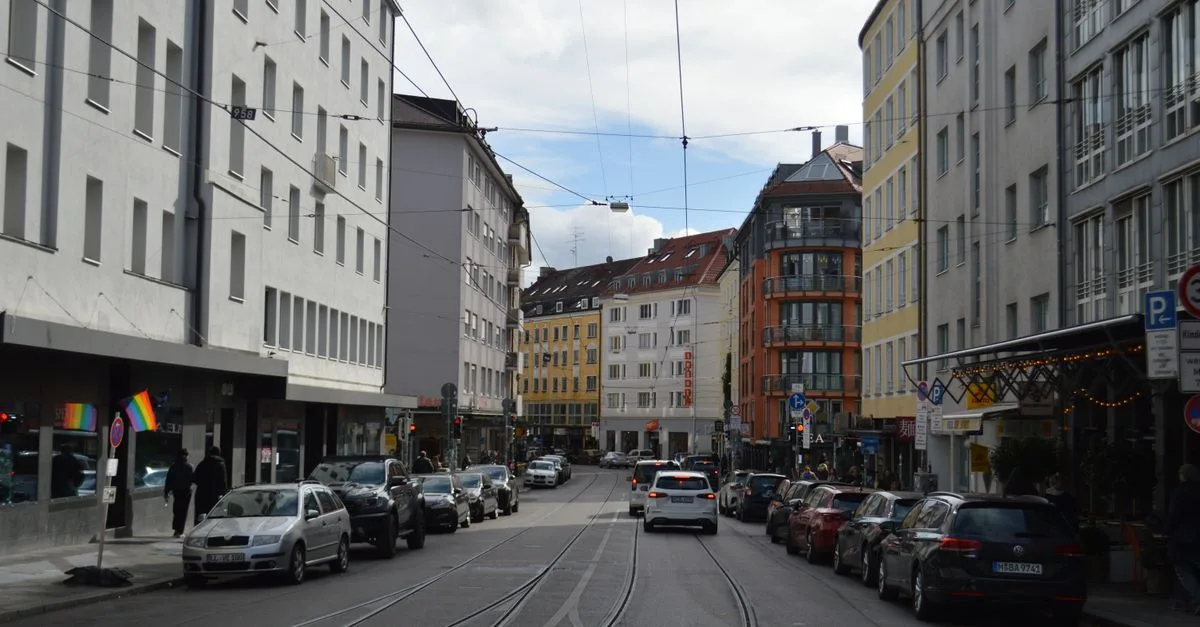 Urban street view with buildings, cars, and tramlines during the day.
