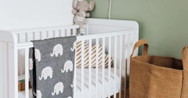 Stylish nursery featuring a cozy white crib with a cute elephant blanket.