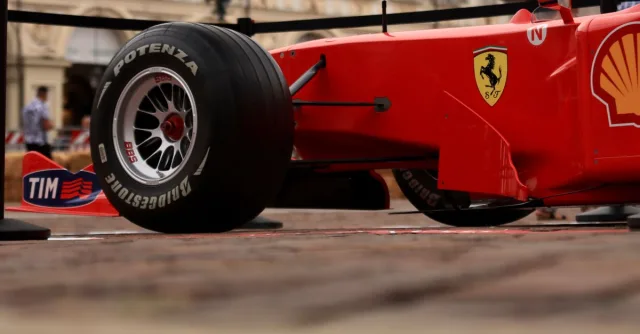 Close-up shot of a red Formula 1 racing car with visible brand logos and Bridgestone tire.
