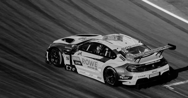 A dynamic black and white photo of a high-speed race car on a track, capturing motion and speed.