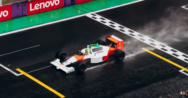 A classic Formula One car races on a wet track, capturing the thrill of motorsport.
