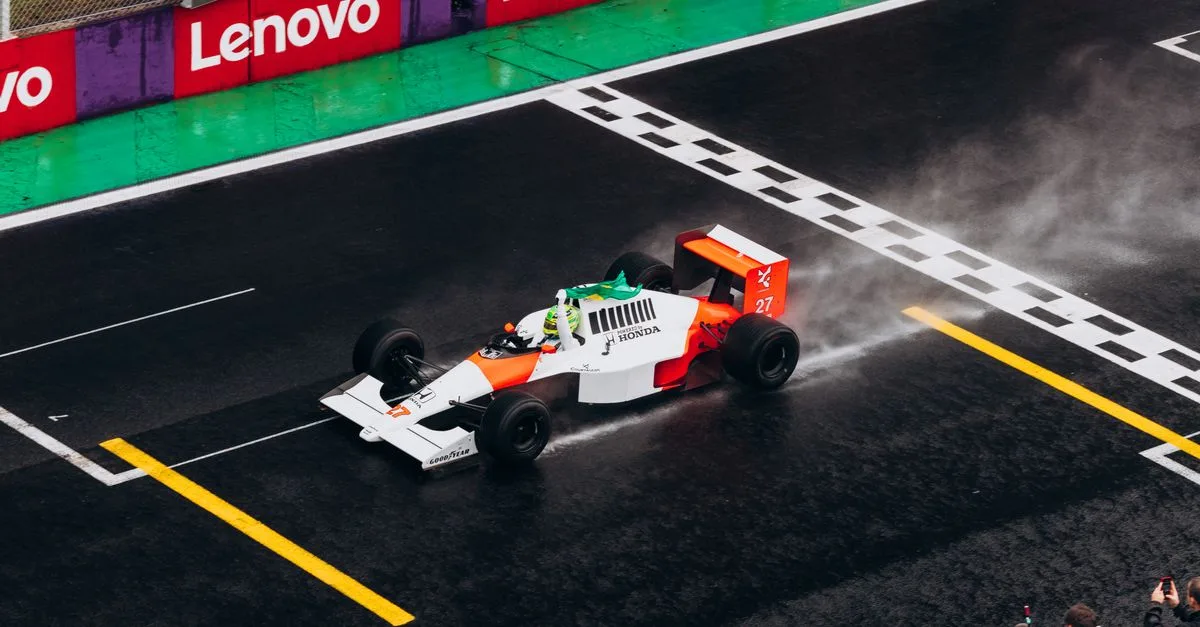 A classic Formula One car races on a wet track, capturing the thrill of motorsport.