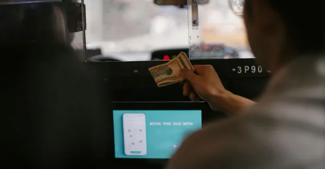 Back view of taxi car interior with tablet screen located near passenger seat and client paying for ride