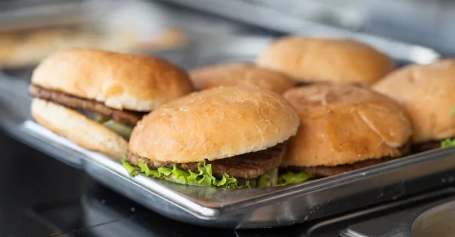 Appetizing close-up of freshly made burgers on a stainless steel tray, ready to serve.