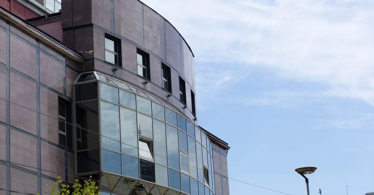 Contemporary building exterior featuring large glass windows under a clear blue sky.