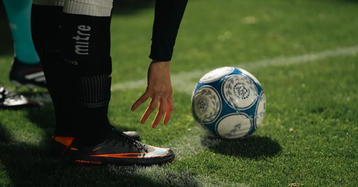 A soccer player in athletic gear prepares for a throw-in during a nighttime match on a grassy field.