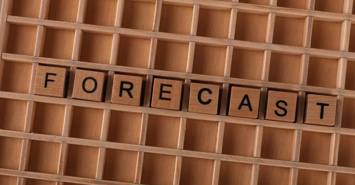 Scrabble-like wooden blocks spelling the word 'forecast' on a wooden grid surface.