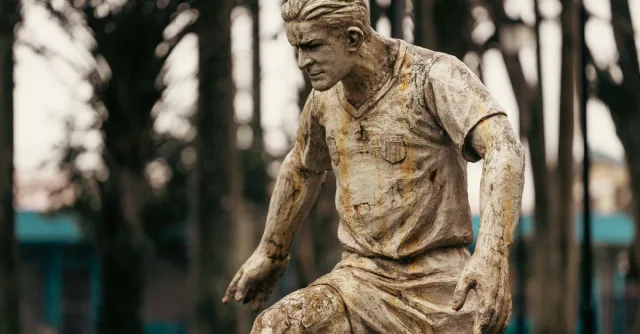 A rustic statue of a soccer player captured in a park in Alajuela, Costa Rica.