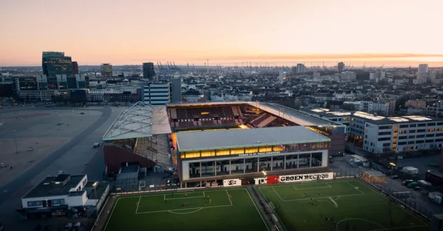 Aerial view of Millerntor-Stadion in Hamburg at sunset, highlighting vibrant city lights.