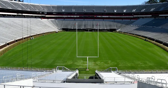 A wide view of a college football stadium field during an autumn afternoon.