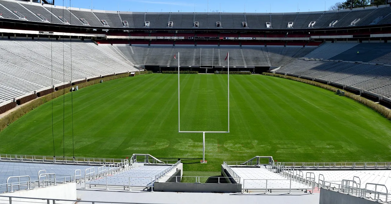A wide view of a college football stadium field during an autumn afternoon.