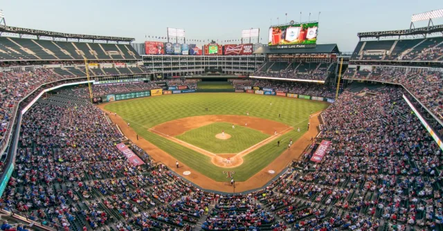 Aerial view of a lively baseball game at the iconic Globe Life Park filled with cheering fans.