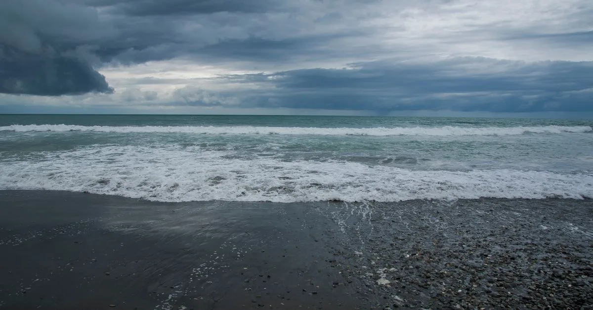Stunning view of a stormy beach with dramatic clouds in New Zealand.