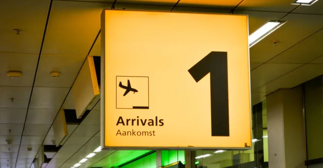 Bright arrivals sign with airplane symbol in an airport terminal.
